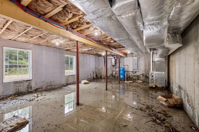Unfinished basement in Union County with flood water and debris on the floor before cleanup