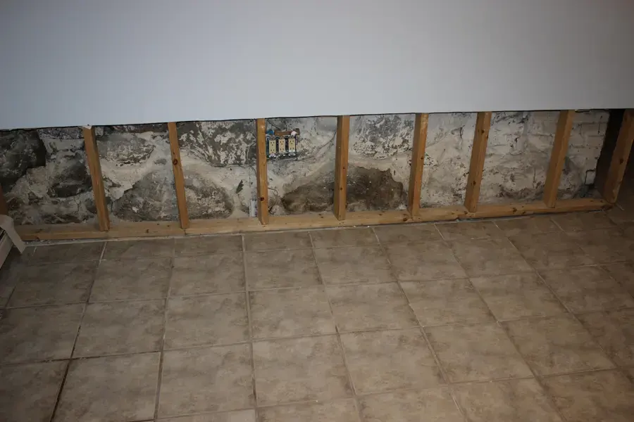 Lower wall cut open above a tile floor during a basement dry-out in Union County