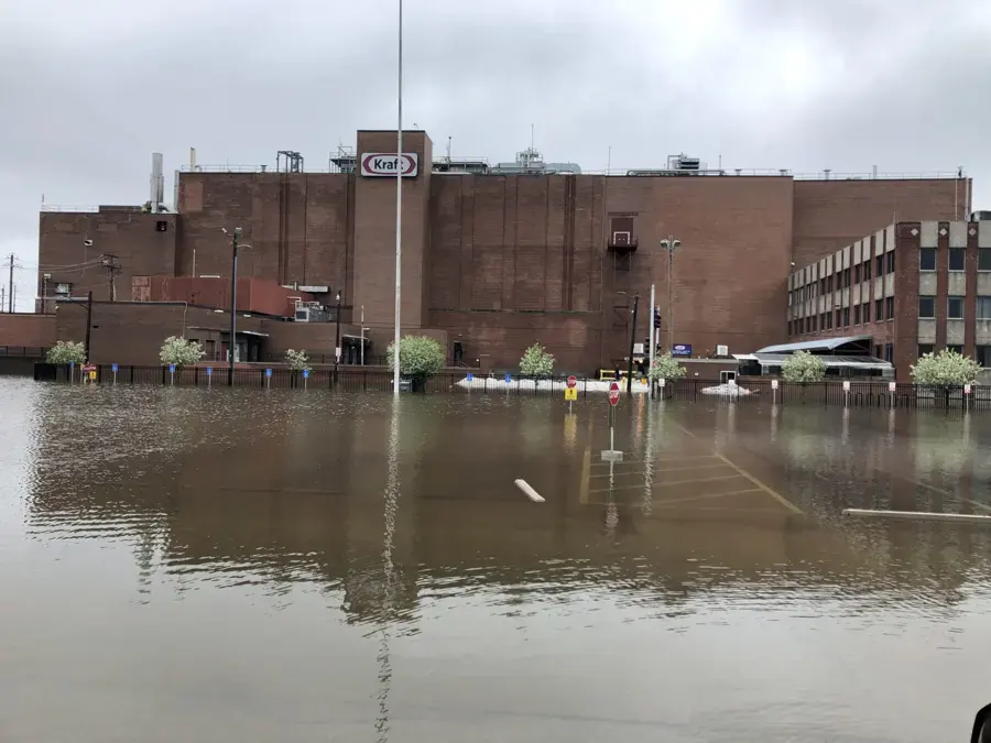 Floodwater covering a street and parking lot in front of a brick industrial building in Union County, NJ