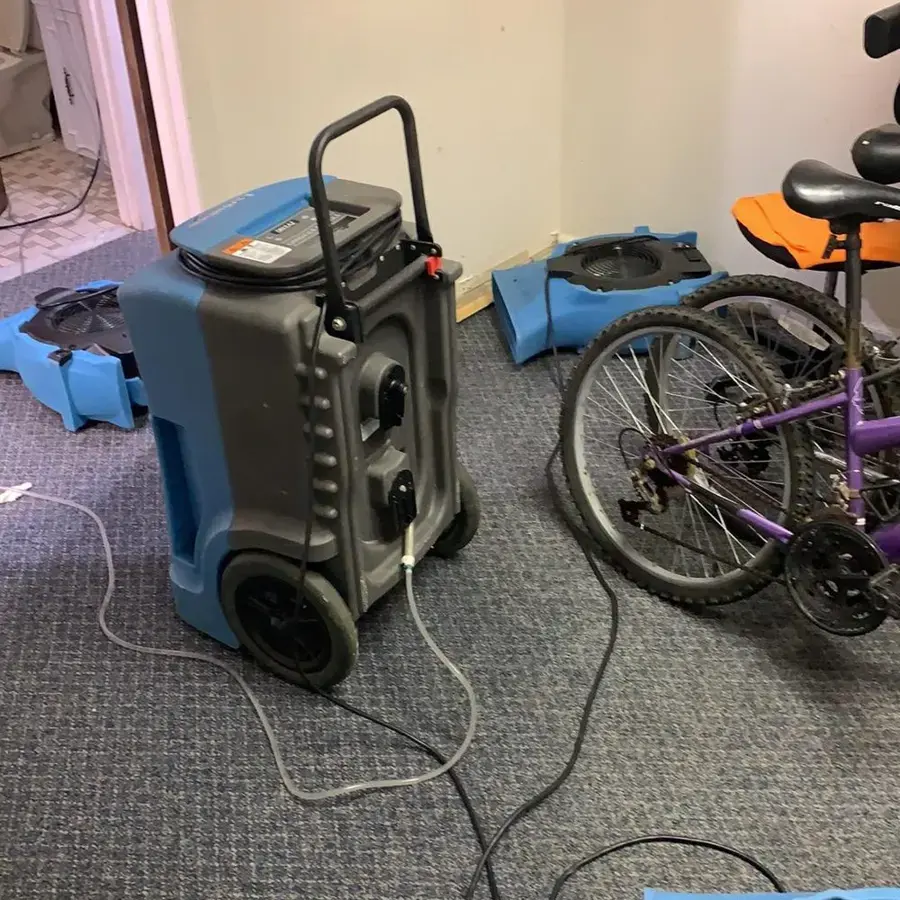Drying equipment, including air movers and a dehumidifier, running in a cleared room during a Linden, NJ water damage job