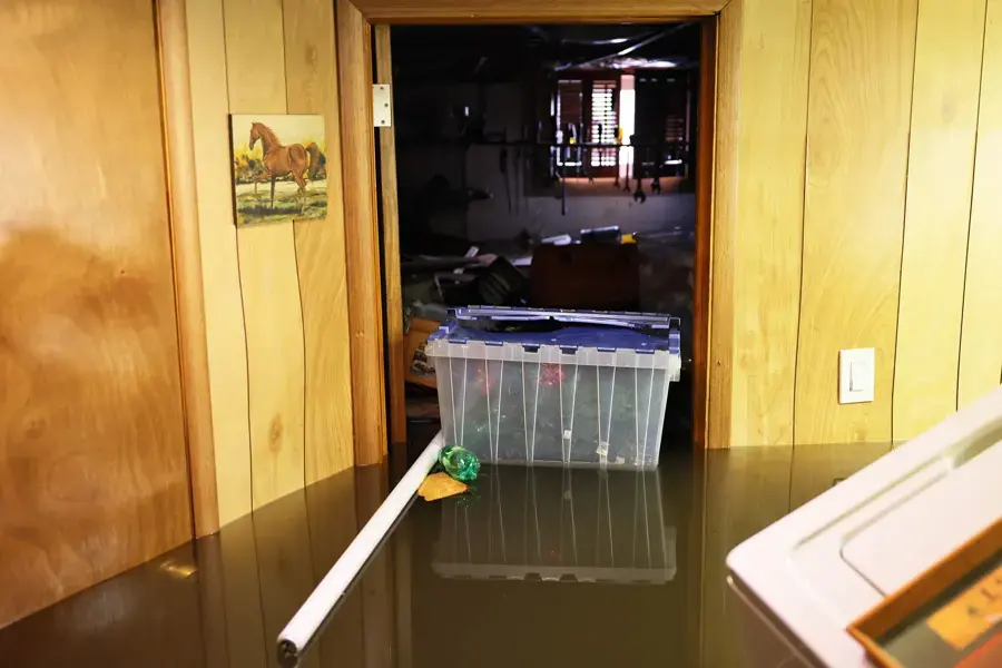 Flood water filling a paneled basement with storage bins floating in Union County, NJ