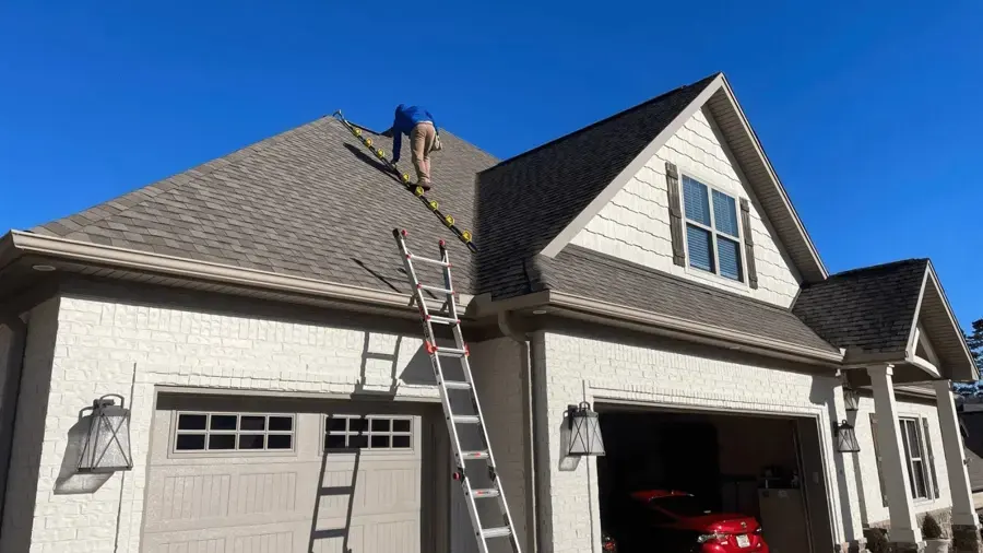 Ladder against a house as a roofer checks the shingles for a roof leak near Union, NJ