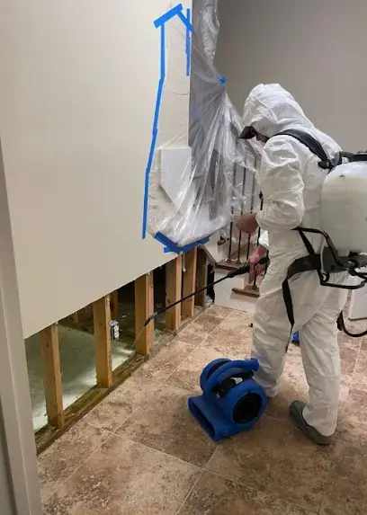 Technician in a protective suit working behind plastic containment during sewage cleanup in Union, NJ