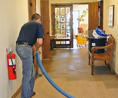 Technician running an extraction hose across a wet floor during water removal in a Union, NJ home